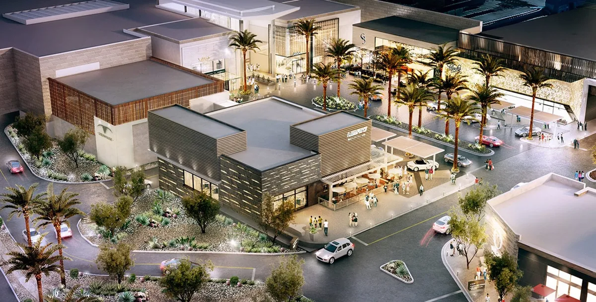 A modern exterior with palm trees framing a stylish building, bustling with people socializing at outdoor seating areas. String lights twinkle above, and nearby shops line the ground floor, capturing the essence of a lively urban scene.