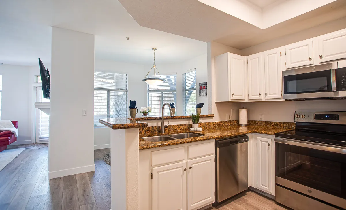This image showcases a modern kitchen with granite countertops, stainless steel appliances, a central island, and a window letting in natural light. The space is open and inviting, designed for both cooking and socializing, and easily accommodates family gatherings or casual dining.