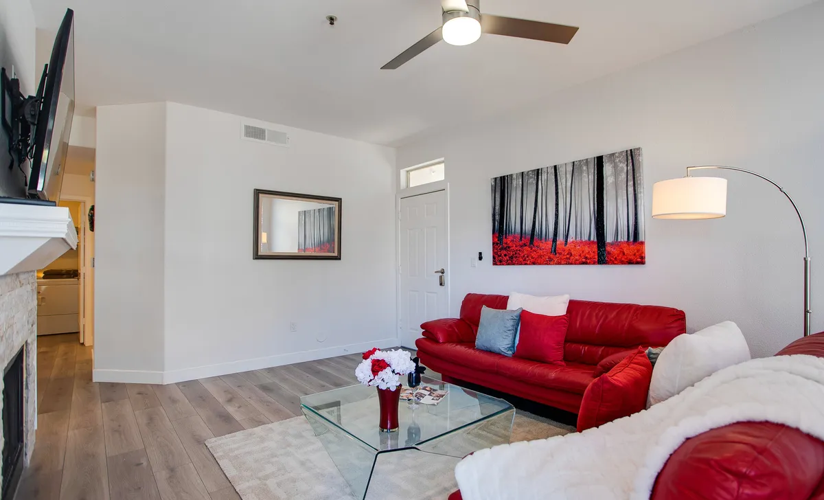 A living room with modern red leather sofas, a coffee table topped with flowers, and an abstract art piece. The space is designed for comfort and relaxation, with plenty of seating for guests or family gatherings.