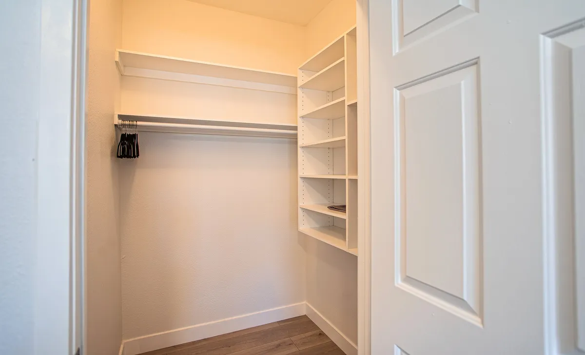 A compact closet space with open shelves and a hanging rod is shown, perfect for storing clothes and accessories efficiently. The uncluttered layout promotes a sense of order and accessibility.