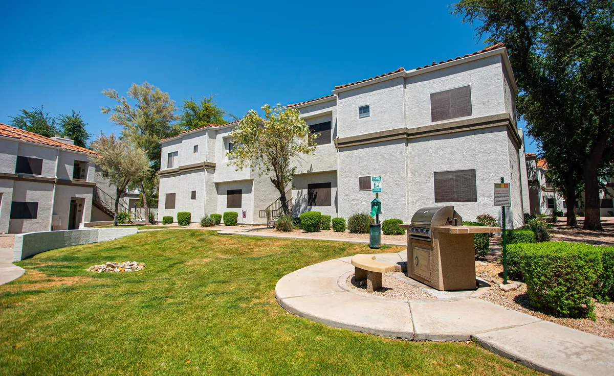 This image showcases the outdoor amenities: a grilling area, green lawn, benches, and trees. The relaxed, communal setting emphasizes opportunities for restorative moments outdoors, whether enjoying a meal, socializing, or simply relaxing in the fresh air.
