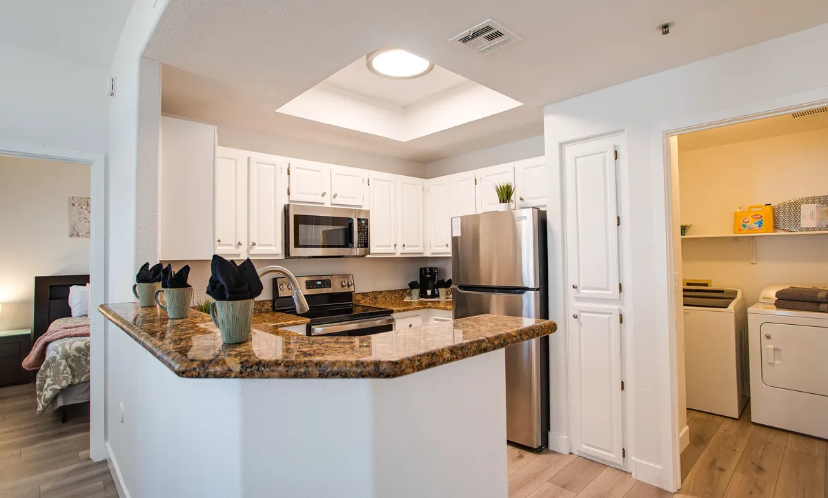 A modern kitchen with a kitchen island, granite countertop, and stainless steel appliances, perfect for cooking, entertaining, and family gatherings. The space is designed for both practicality and style.